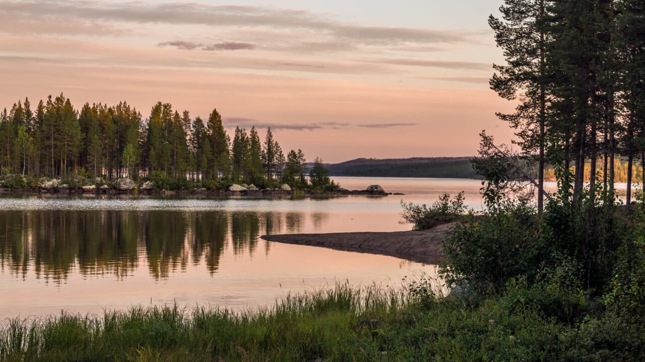 Sunset in marshland and pines surrounded by the mountains of the Muddus national park, Norrbotten ...